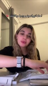 Young woman with wavy blonde hair demonstrating a smartwatch on her wrist.