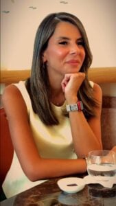 Elegant woman wearing smartwatch at dining table, showcasing stylish accessories.