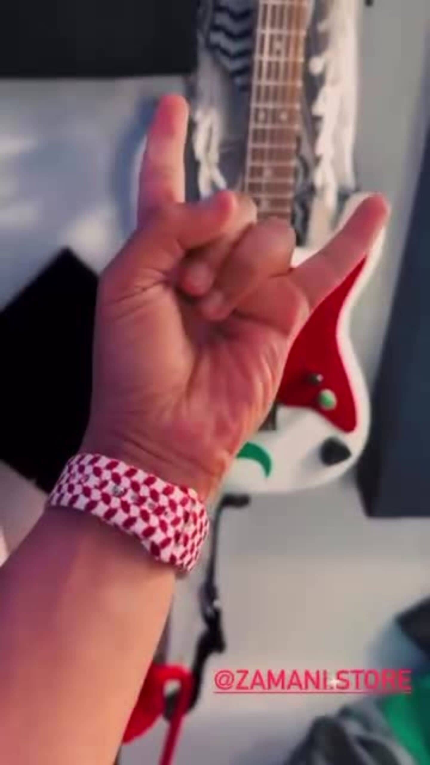 Rock on hand gesture with a guitar in the background, emphasizing music style and self-expression.