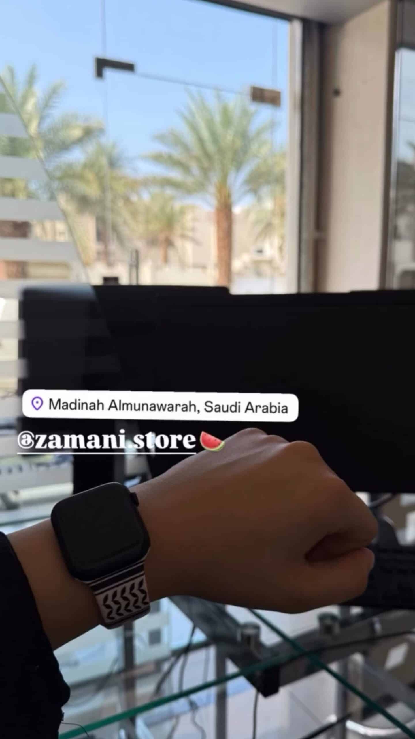1. Smartwatch on wrist with view of palm trees outside window in Saudi Arabia.