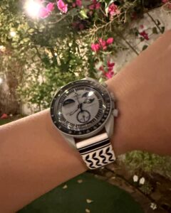 MoonSwatch with zamani Classic Keffiyeh band on wrist with bougainvillea