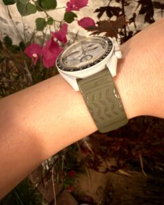 MoonSwatch with zamani Olive Engraved Keffiyeh band on wrist in garden